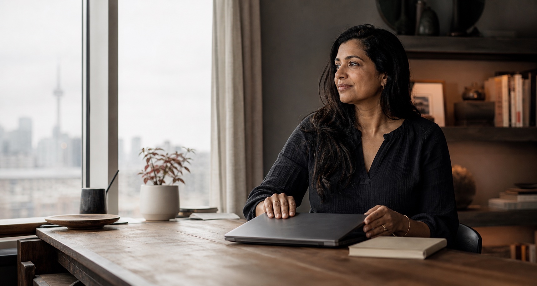 A self-employed professional closing a laptop beside an open notebook